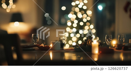Warmly lit festive dinner table with candles, glassware, and bokeh Christmas tree lights in the background. Ideal for holiday ads, celebration visuals, cozy interiors or seasonal lifestyle content. 126620737
