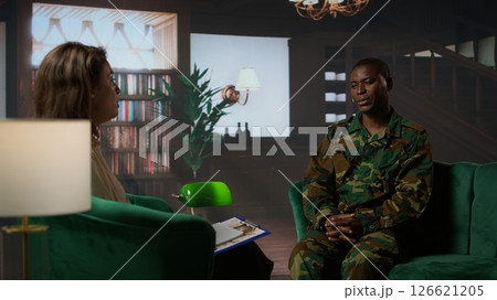 African american serviceman suffering from post traumatic stress disorder after army combat, therapy session with expert. Infantry trooper deals with shell shock, psychological care. Camera A. African american serviceman suffering from post traumatic stress disorder after army combat, therapy session with expert. Infantry trooper deals with shell shock, psychological care. Camera A. 126621205