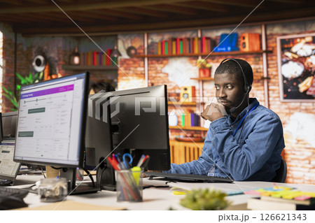 Call center staff member tracking shipments in office, looking at PC screen. African american customer center employee using software to locate clients packages and provide status updates 126621343