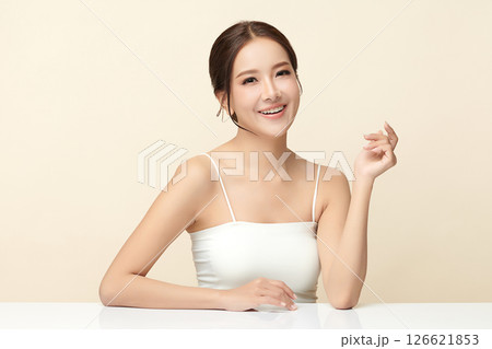 A beautiful young Asian woman with clean, fresh skin against a beige background. Skincare, facial treatment, cosmetology, beauty, and spa. An elegant portrait of an Asian woman. 126621853