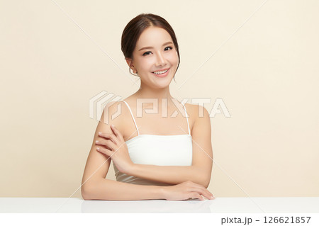 A beautiful young Asian woman with clean, fresh skin against a beige background. Skincare, facial treatment, cosmetology, beauty, and spa. An elegant portrait of an Asian woman. 126621857