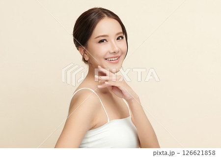 A beautiful young Asian woman with clean, fresh skin against a beige background. Skincare, facial treatment, cosmetology, beauty, and spa. An elegant portrait of an Asian woman. 126621858