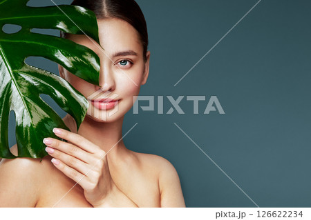 Close up woman face with green exotic leaf Close up woman face with green exotic leaf 126622234