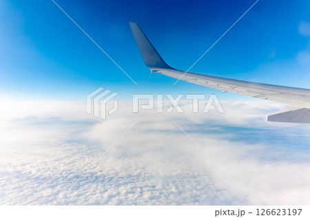 View from the airplane window at a beautiful cloudy sky and the airplane wing 126623197