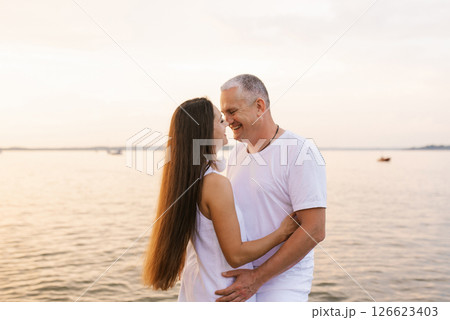 Couple is hugging on beach with the ocean in the background Couple is hugging on beach with the ocean in the background 126623403