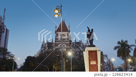 Mumbai, India. People Walk Throw Hutatma Chowk Or Martyrs Square. Square Hosts Flora Fountain. Statue Of Martyr With Flame Stands Next To Flora Fountain. Dusk In City. Busy Traffic In City Street Mumbai, India. People Walk Throw Hutatma Chowk Or Martyrs Square. Square Hosts Flora Fountain. Statue Of Martyr With Flame Stands Next To Flora Fountain. Dusk In City. Busy Traffic In City Street 126623414