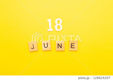 Top view of word 18 June calendar date made by wooden cubes on yellow color background Top view of word 18 June calendar date made by wooden cubes on yellow color background 126624207
