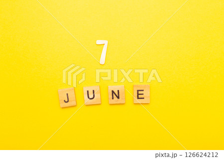 Top view of word 7 June calendar date made by wooden cubes on yellow color background Top view of word 7 June calendar date made by wooden cubes on yellow color background 126624212