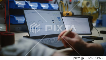 Craftsman Doing Handwork, Monitoring Stocks on Laptop and Tablet Computer in Workshop Craftsman Doing Handwork, Monitoring Stocks on Laptop and Tablet Computer in Workshop 126624922