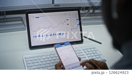 Stock Exchange Trader Analyzing Exchange Market Charts on Smartphone and Tablet Computer 126624923