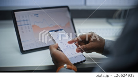 Stock Exchange Broker Analyzing Exchange Market Charts on Smartphone and Digital Tablet Stock Exchange Broker Analyzing Exchange Market Charts on Smartphone and Digital Tablet 126624935