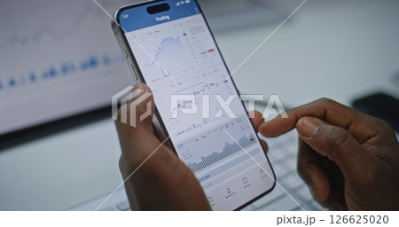 Close Up of Stock Exchange Trader Monitoring Real-Time Stocks on Smartphone and Tablet Computer 126625020