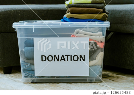 Donation boxes with clothes and shoes on floor against sofa in the apartment 126625488