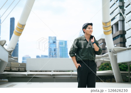 Confident young businessman walking outdoors with a jacket over his shoulder 126626230