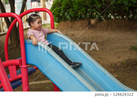 happy toddler baby girl sliding and playing at playground 126626322