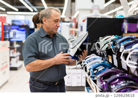 Elderly man chooses iron in store Elderly man chooses iron in store 126628618