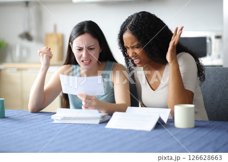 Angry women checking bank statement at home Angry women checking bank statement at home 126628663