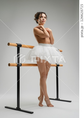 Graceful ballet dancer poses in natural light with a backdrop of shadows 126628715