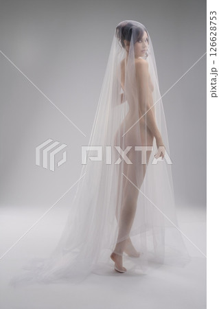 Woman dressed in sheer veil posing elegantly in a minimalist setting Woman dressed in sheer veil posing elegantly in a minimalist setting 126628753