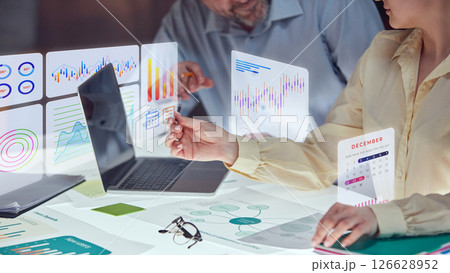 Conceptual collage. Team collaboration at futuristic desk with holographic charts, calendar widgets and graphs floating in air, showing financial planning 126628952