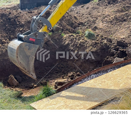 Close up view of excavator bucket digging ground on construction site Close up view of excavator bucket digging ground on construction site 126629365