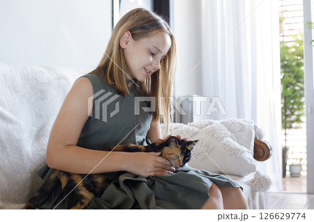 Excited young girl hugging her cat pet sitting on cosy sofa, relaxing at home. Excited young girl hugging her cat pet sitting on cosy sofa, relaxing at home. 126629774