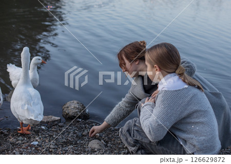 Outdoors portrait of woman and child with birds in park. Happy family Outdoors portrait of woman and child with birds in park. Happy family 126629872