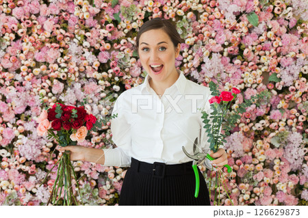 Beautiful female florist showing flowers Beautiful female florist showing flowers 126629873