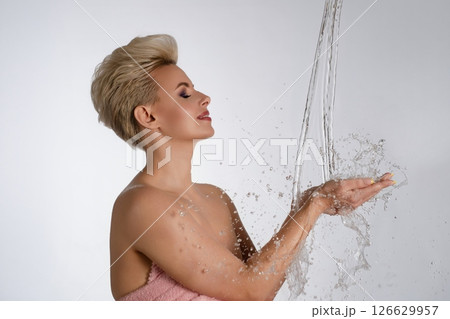 Elegant woman enjoying water splashes against a clean backdrop in soft lighting Elegant woman enjoying water splashes against a clean backdrop in soft lighting 126629957