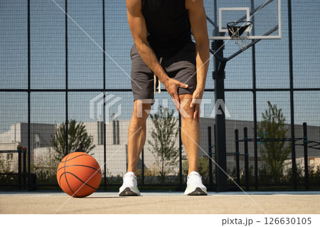 Basketball ankle injury or pain. Professional athlete or sportsman with accident. Basketball player check knee after workout of sport stadium. Man check pain in leg after sport workout. Basketball ankle injury or pain. Professional athlete or sportsman with accident. Basketball player check knee after workout of sport stadium. Man check pain in leg after sport workout. 126630105