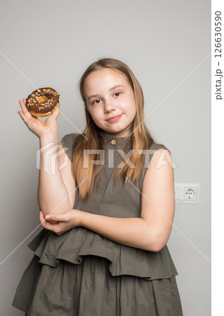 Cheerful child kid girl 10-11 years old wearing casual clothes have fun with donuts Cheerful child kid girl 10-11 years old wearing casual clothes have fun with donuts 126630590