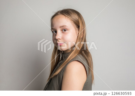 Portrait of young child girl standing against white wall background 126630593