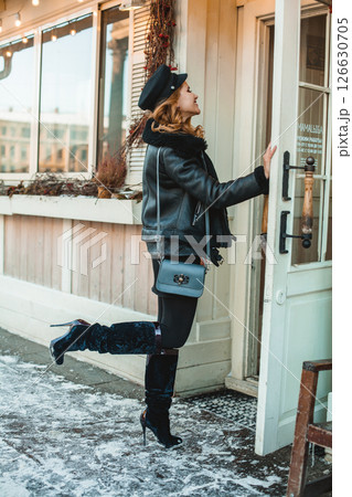 Pretty brunette woman in black leather jacket and high heels on the background of winter snow city Pretty brunette woman in black leather jacket and high heels on the background of winter snow city 126630705