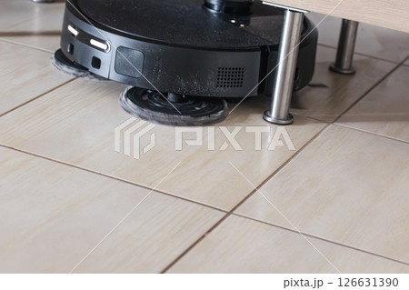 Robot vacuum cleaner with dust, real life photo, saves time and goes into hard-to-reach places 126631390