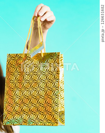 Woman holds golden gift bag in hand 126631682