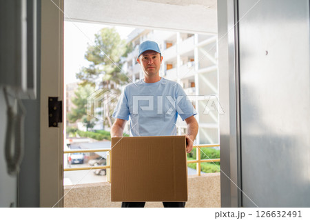 A male courier in a blue uniform with a parcel in his hands. A male courier in a blue uniform with a parcel in his hands. 126632491