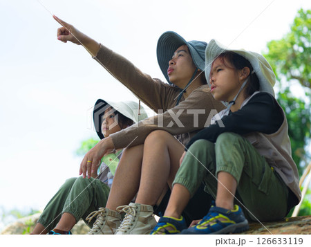 Asian mother takes her children to learn about nature in the forest to explore nature from the real place. Mother and children are enjoying nature outdoors, adventuring in the forest. Asian mother takes her children to learn about nature in the forest to explore nature from the real place. Mother and children are enjoying nature outdoors, adventuring in the forest. 126633119