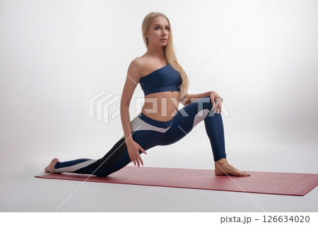 Woman practicing yoga in sport attire in a studio setting Woman practicing yoga in sport attire in a studio setting 126634020