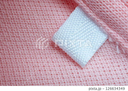 White blank laundry care clothes label on pink shirt fabric background White blank laundry care clothes label on pink shirt fabric background 126634349