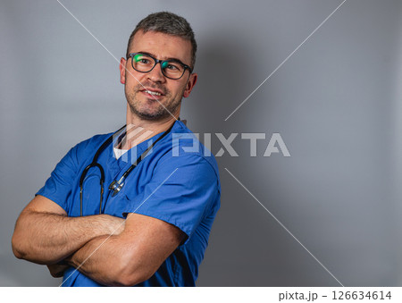 Smiling healthcare professional wearing scrubs and glasses poses confidently 126634614