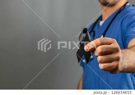 Healthcare worker holds a black ribbon symbolizing grief and remembrance Healthcare worker holds a black ribbon symbolizing grief and remembrance 126634655