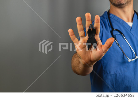 Healthcare worker holding a black ribbon to honor those affected by loss 126634658