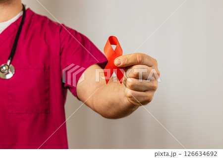 Healthcare worker holding red ribbon symbolizing awareness for HIV/AIDS Healthcare worker holding red ribbon symbolizing awareness for HIV/AIDS 126634692