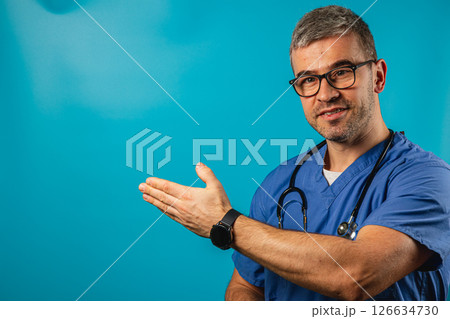 Healthcare professional in scrubs gestures toward a bright background 126634730