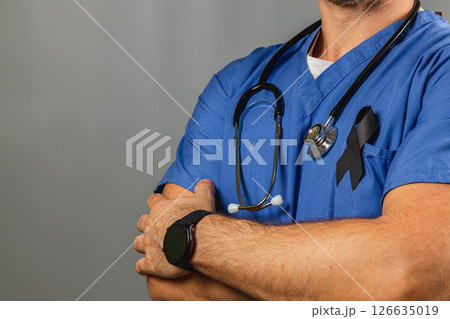 Healthcare worker in blue uniform with black ribbon at memorial Healthcare worker in blue uniform with black ribbon at memorial 126635019