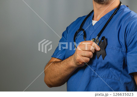 Healthcare worker honors lost lives with black ribbon during solemn tribute 126635023