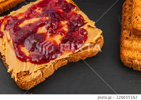 Peanut butter and jelly spread on whole grain bread slices Peanut butter and jelly spread on whole grain bread slices 126635162