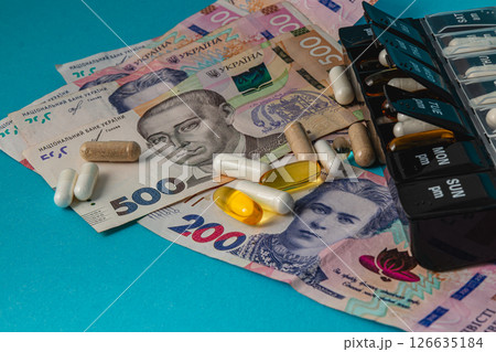 Money and medicine displayed together on colorful surface Money and medicine displayed together on colorful surface 126635184
