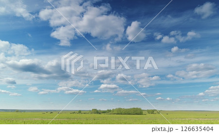 A Beautiful Expansive Sky and Lush Green Fields Stretching Under Bright, Fluffy Clouds Time lapse. 126635404