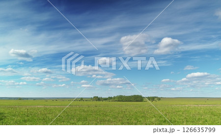 A vast and open field stretches out beneath a bright and beautiful blue sky filled with sunlight Time lapse. 126635799